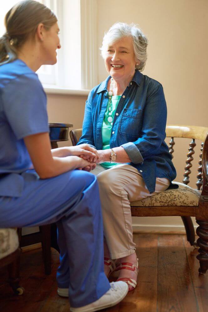 Female Nurse Comforting Elderly Woman at Assisted Living Facility Female Nurse Comforting Elderly Woman at Assisted Living Facility