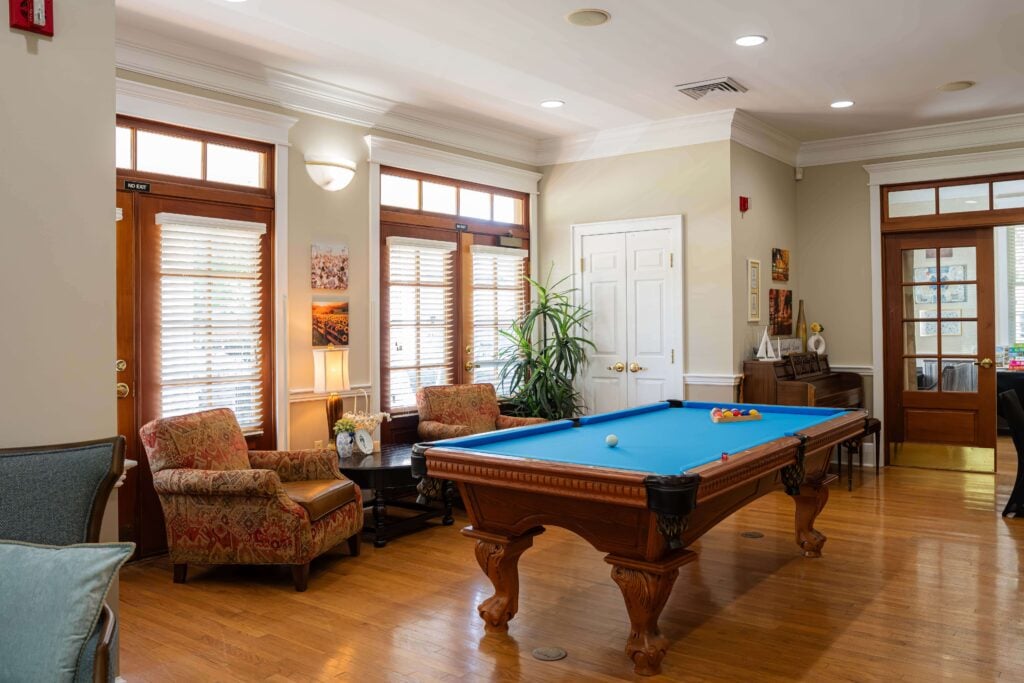 Game Room With Billiards Table and Armchairs at Assisted Living Facility